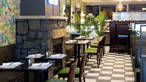 Un restaurant avec un sol à carreaux, un mur en pierre et des chaises rembourrées de couleur verte.
