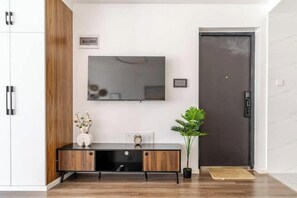 Un interior moderno con un mueble de madera, un televisor de pantalla plana montado en la pared y una puerta oscura.