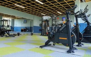 Un gimnasio con equipamiento de ejercicio, incluyendo una jaula para sentadillas y máquinas de cardio.