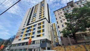 Un immeuble à plusieurs étages doté d’une architecture moderne, comprenant un mélange d’espaces résidentiels et commerciaux.