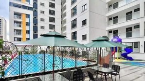 Un espace aménagé au bord de la piscine, avec des sièges extérieurs et une aire de jeux pour enfants.