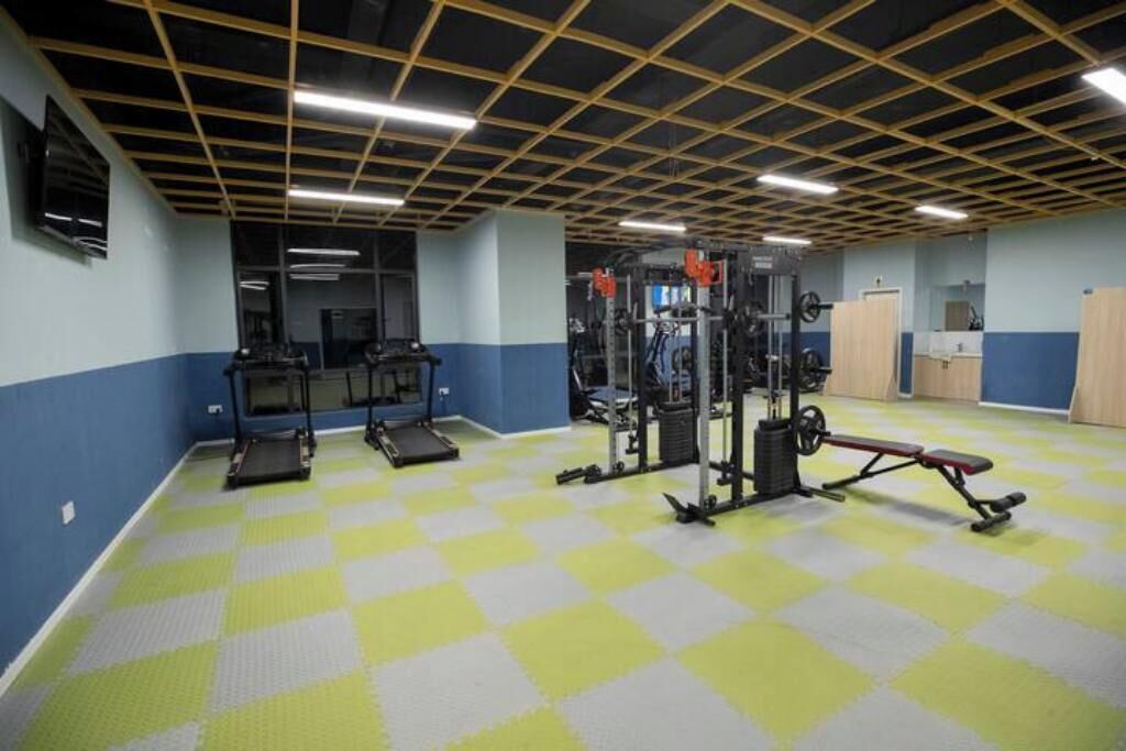 Une salle de sport équipée de matériel d’exercice, d’un tapis de course et d’un banc de musculation.