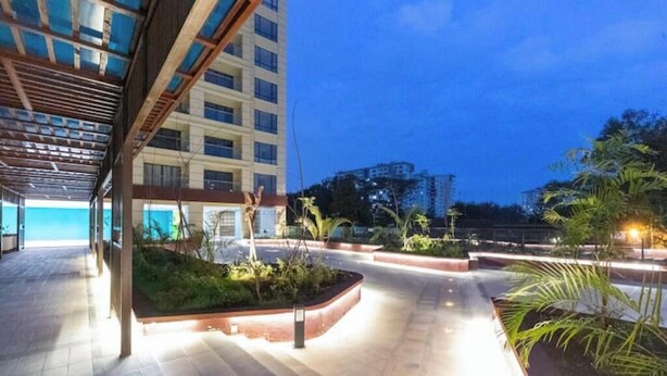 An outdoor area with a covered walkway, planters, and a building in the background.