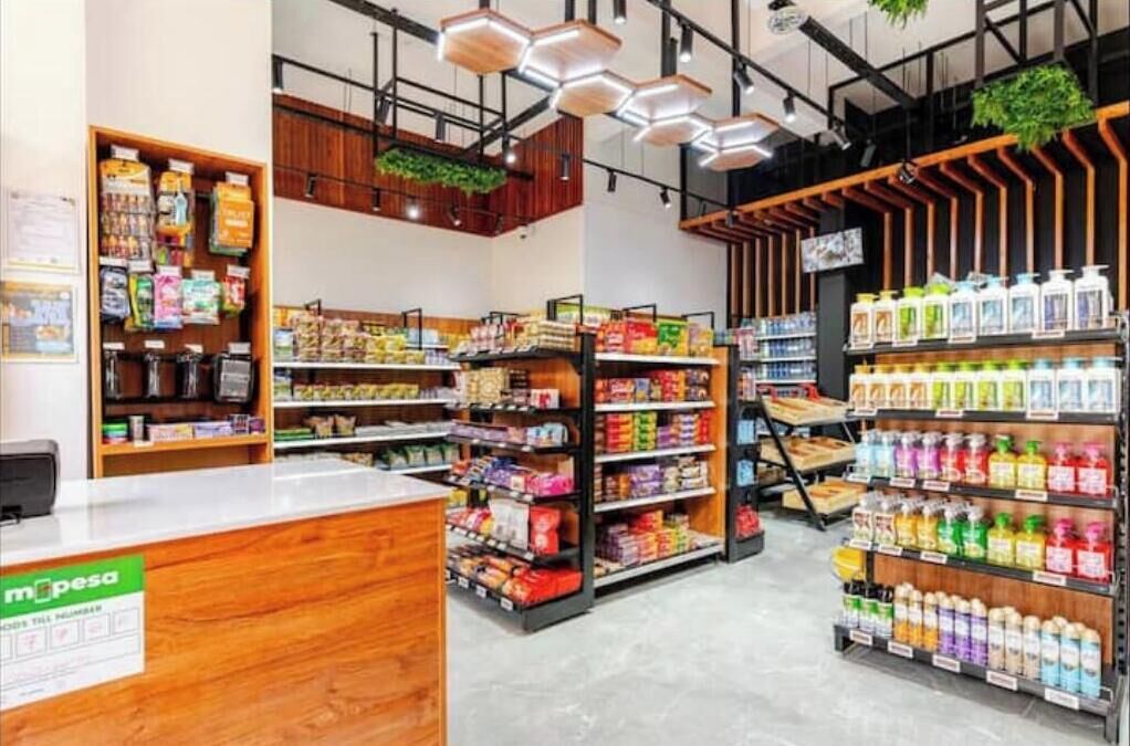 Una tienda minorista moderna con estanterías de madera y una variedad de productos, incluyendo bocadillos, bebidas y artículos para el hogar.