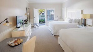 Een hotelkamer met een bed, een bureau met lamp, een stoel, een kleintje tafeltje met eten erop, en een raam met jaloezieën.