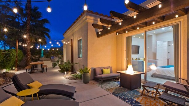 Un patio al aire libre con sillones de descanso, una chimenea y guirnaldas de luces.