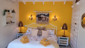 Ein Bett mit vielen Kissen, eine Nachttischlampe, ein an der Wand hängendes Bild und ein Regal mit Dekoration.