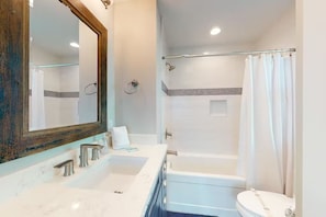 A modern bathroom with a double sink, a bathtub, and a toilet.