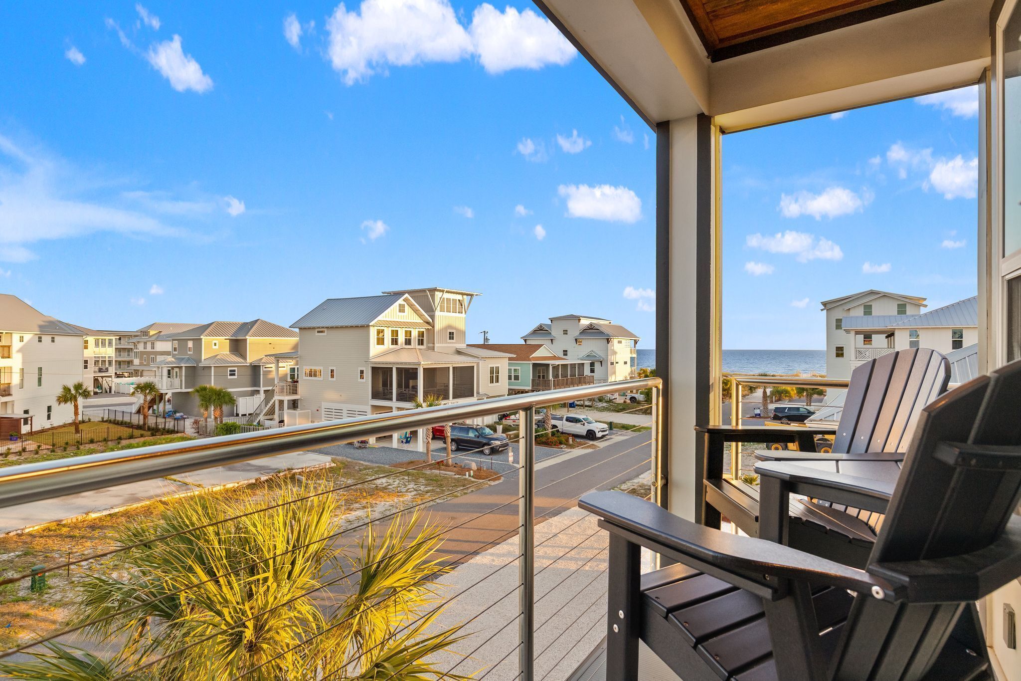 A balcony with a view of a coastal residential area, including houses and a road.