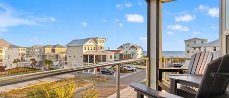 A balcony with a view of a coastal residential area, including houses and a road.