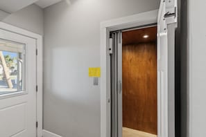 Ein Korridor mit einer weißen Tür, einer Holztür und einem gelben Schild an der Wand.