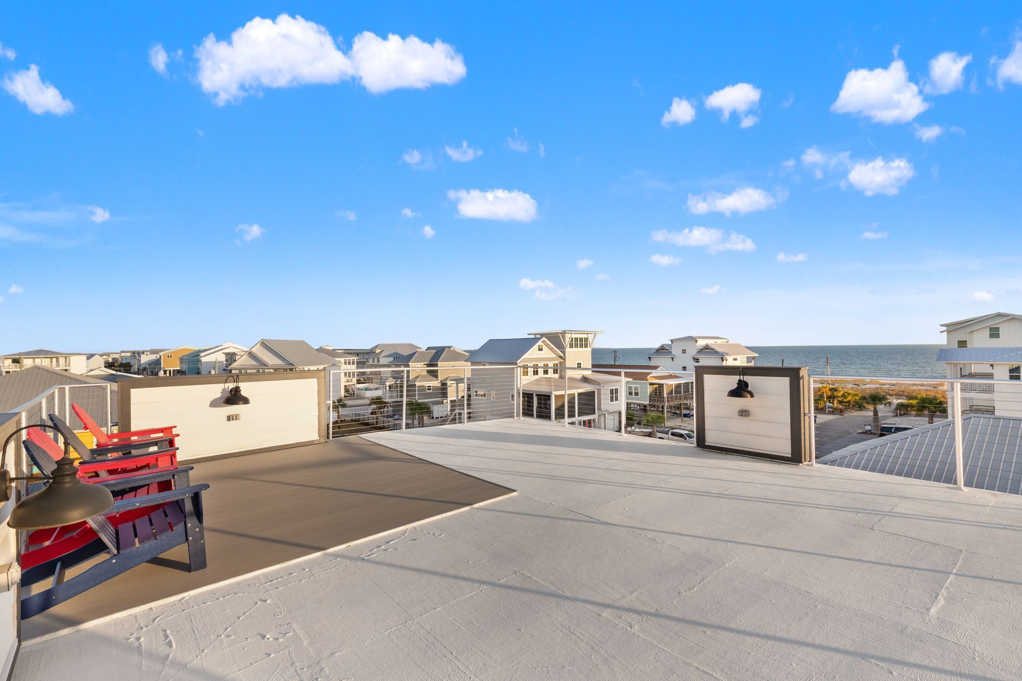 A rooftop with a clear view of the ocean, featuring a variety of buildings and a red and black structure.