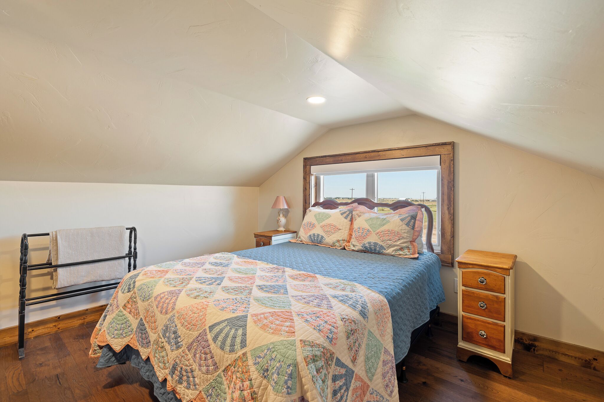 Un dormitorio con cama, mesita de noche, cómoda de madera, ventana y ventilador de techo.