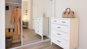 Huoneessa on vaatekaappi, työpöytä, tuoli ja henkarissa oleva kaapu.
