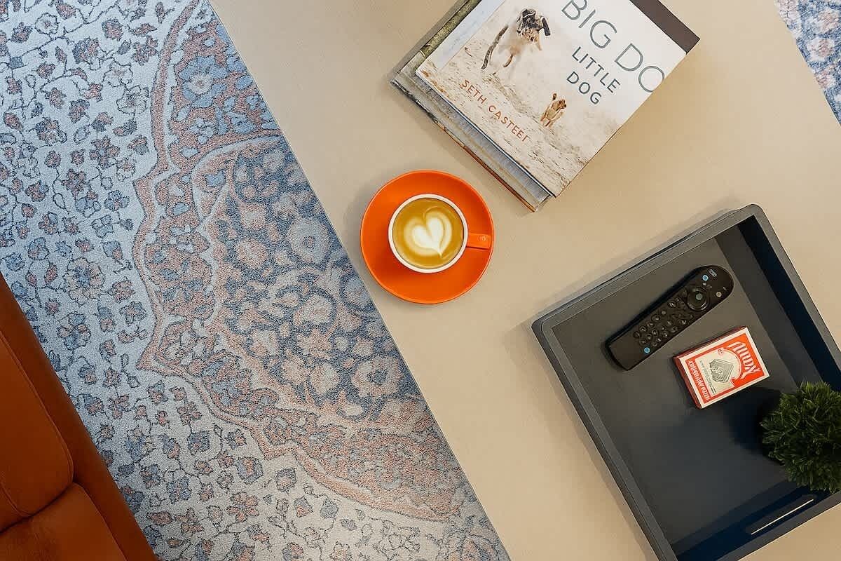 A book titled 'BIG DOG LITTLE DOG' by Seth Casteel, a cup of coffee with a heart design, and a remote control on a table.