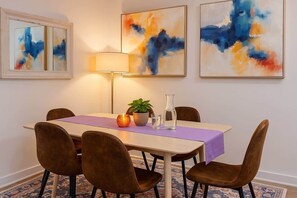 A dining area with a table, chairs, a lamp, and abstract art on the wall. - 5 Beds 1500 Sq ft Walkable Kitchen 1 and a half Bath (Conshohocken)