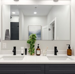 A bathroom with two sinks, a large mirror, a potted plant, and toiletries. - 5 Beds 1500 Sq ft Walkable Kitchen 1 and a half Bath (Conshohocken)