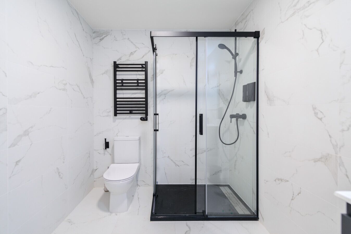 Ein modernes Badezimmer mit einer Duschkabine, einer Toilette und einem Handtuchhalter.