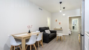 Un salon moderne comprenant une table à manger, des chaises, un canapé et un coin cuisine avec un réfrigérateur.
