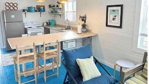Une cuisine compacte avec un îlot central, des chaises en bois, un canapé bleu et une petite table.