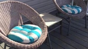Two wicker chairs with blue and white cushions on a wooden deck. - Point Break Historic Beach Cottage (Carolina Beach)