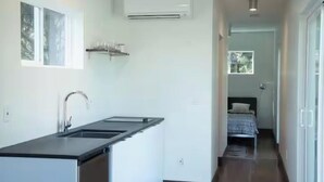 A narrow hallway with a kitchen area on one side, featuring a sink and an air conditioner. - Two Modern Containers-walk to the beach-Two blocks to the beach-Pet Friendly (Carolina Beach)