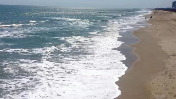 A beach with waves crashing onto the shore, a clear sky, and a distant shoreline. - Two Modern Containers-walk to the beach-Two blocks to the beach-Pet Friendly (Carolina Beach)