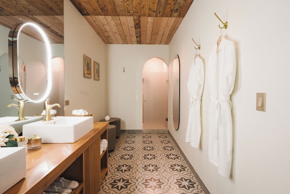 Une salle de bain avec un meuble-lavabo en bois, un grand miroir et un sol carrelé.
