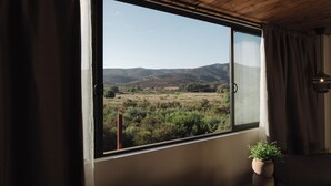 A room with a large window offering a view of a hilly landscape. - Casa Frida (Valle de Guadalupe)