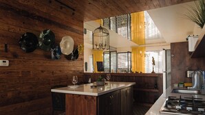 A kitchen with wooden walls, a central island, and a modern stove. - Casa Frida (Valle de Guadalupe)