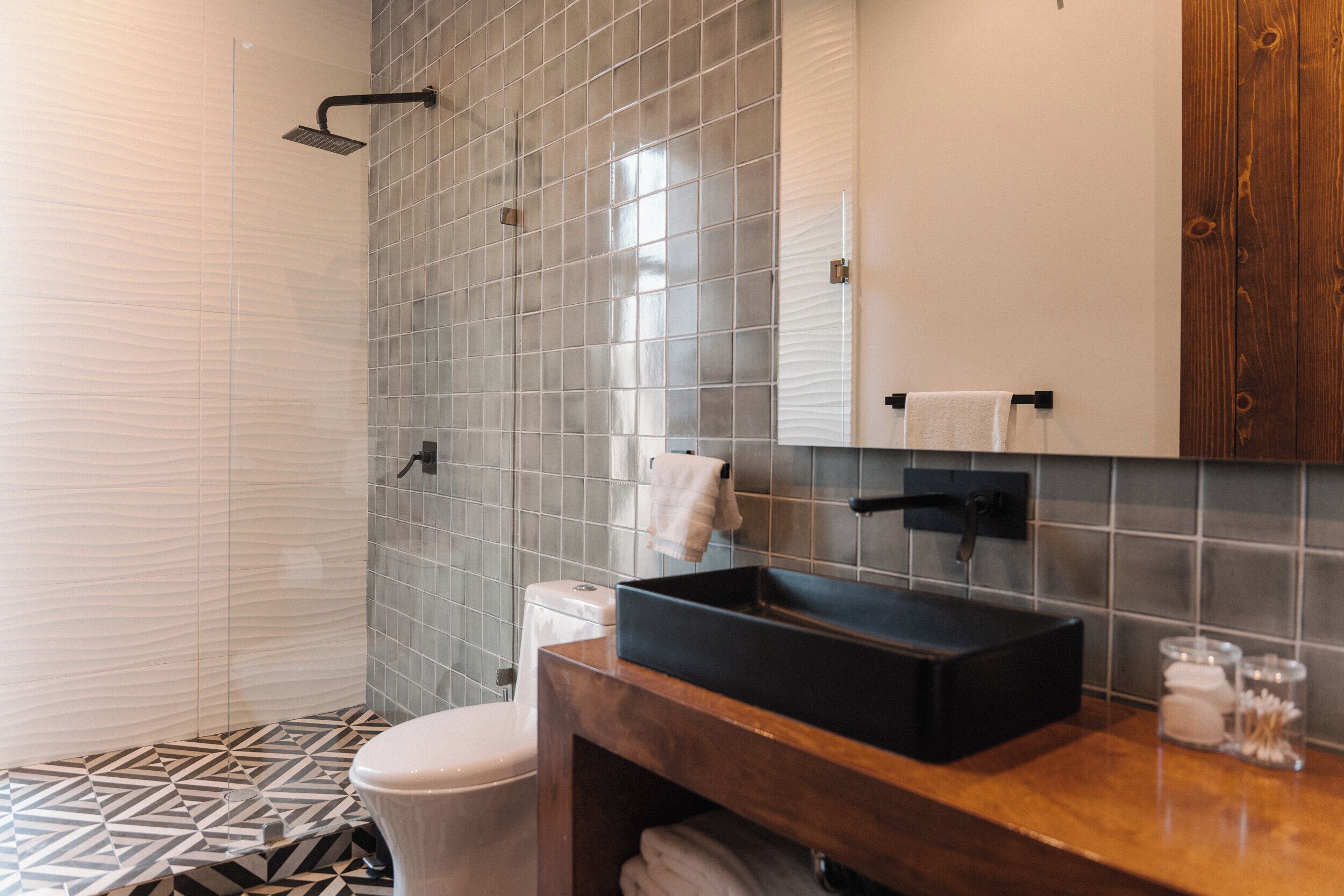 A bathroom with a shower, toilet, and sink with a mirror above.