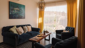 A living room with a dark blue sofa, two armchairs, a wooden coffee table, and a painting of a fish on the wall. - Casa Frida (Valle de Guadalupe)