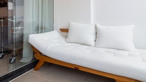 A modern bedroom with a wooden platform bed, white bedding, and a glass shower enclosure.