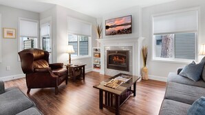 A living room with a fireplace, a leather armchair, a sofa, and a coffee table. - Eaglewood 21 Sunriver with Pool,Tennis and Hot Tub (Sunriver)