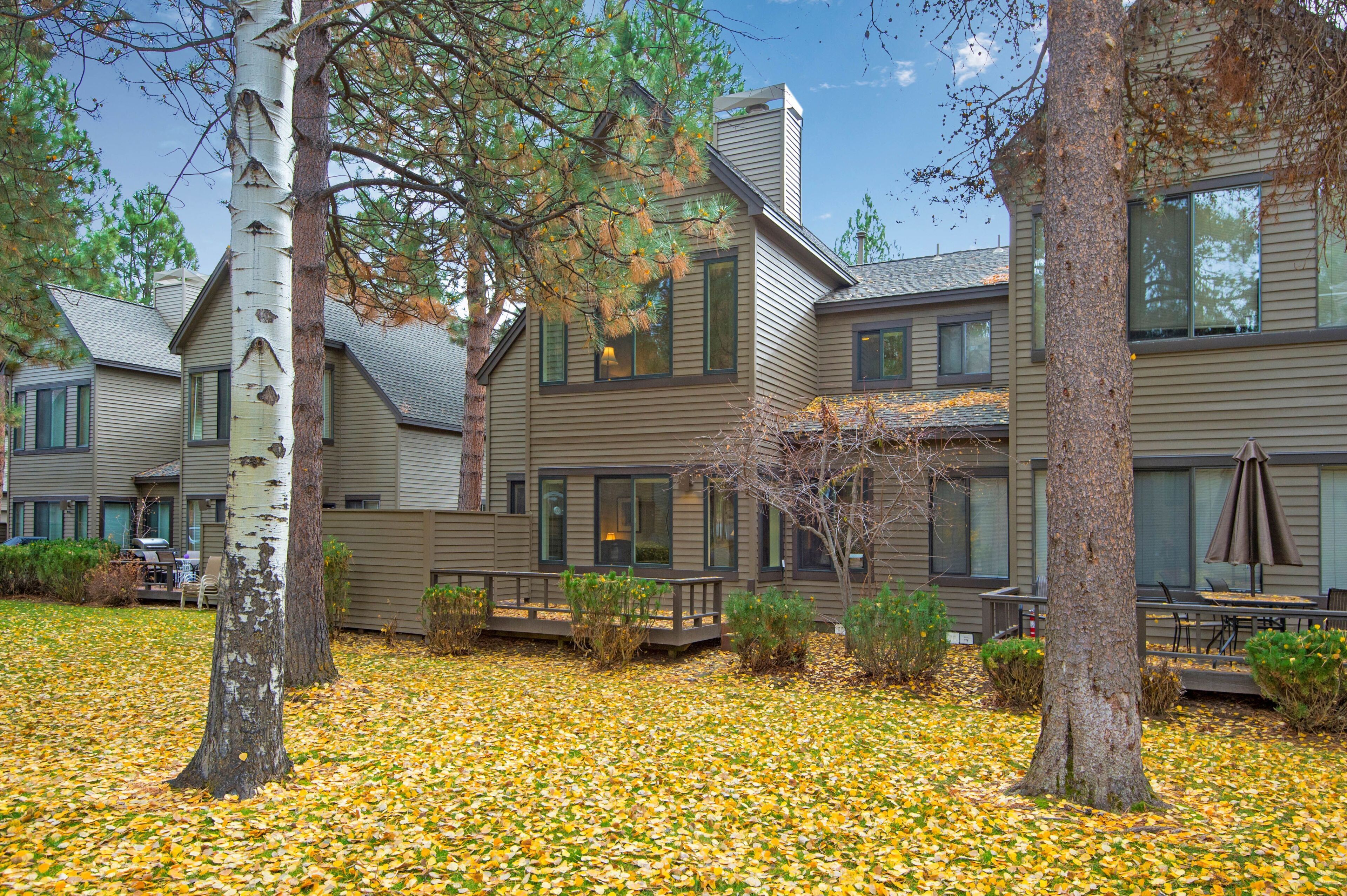 A multi-story building with a covered outdoor area, a wooden deck, and a leaf-covered ground.