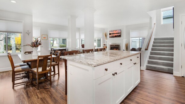 A spacious kitchen with a large island, wooden chairs, and a staircase leading to an upper level. - Eaglewood 21 Sunriver with Pool,Tennis and Hot Tub (Sunriver)