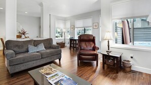 A spacious living room with a grey sofa, a leather armchair, and a coffee table with magazines. - Eaglewood 21 Sunriver with Pool,Tennis and Hot Tub (Sunriver)