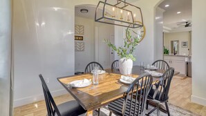 Un comedor con una mesa de madera, sillas negras y un florero central con follaje.