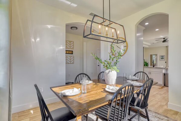 A dining area with a wooden table, black chairs, and a central vase with greenery.