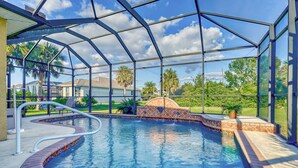 Una piscina techada con techo transparente, rodeada por un suelo de ladrillo y un borde de piedra.
