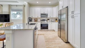 Una cocina moderna con armarios blancos, electrodomésticos de acero inoxidable y encimera de granito.