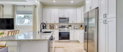 A modern kitchen with white cabinets, stainless steel appliances, and a granite countertop.