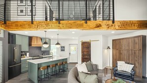 A modern kitchen with a central island, bar stools, and a dining area with a sofa and coffee table. - Luxe Silo w/ River Views <.5 mi to Downtown (Lynchburg)