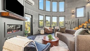 A spacious living area with a fireplace, comfortable seating, and large windows offering views of the outdoors. - Luxe Silo w/ River Views <.5 mi to Downtown (Lynchburg)