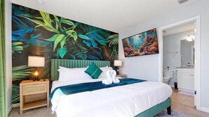 Camera d'albergo con un letto grande, un comodino con una lampada, una testiera verde e un murale a tema tropicale.