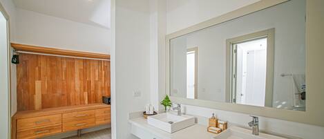 A modern bathroom with a wooden bench, two sinks, and a large mirror.