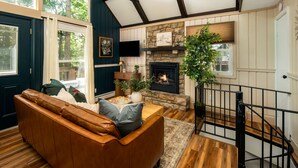 Ein gemütliches Wohnzimmer mit einem Ledersofa, einem Kamin und einer Treppe.