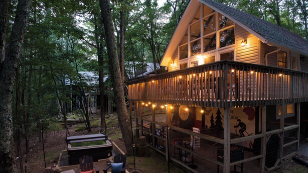 Eine Hütte mit Terrasse, Sitzgelegenheiten im Freien und einem Feuerkorb.