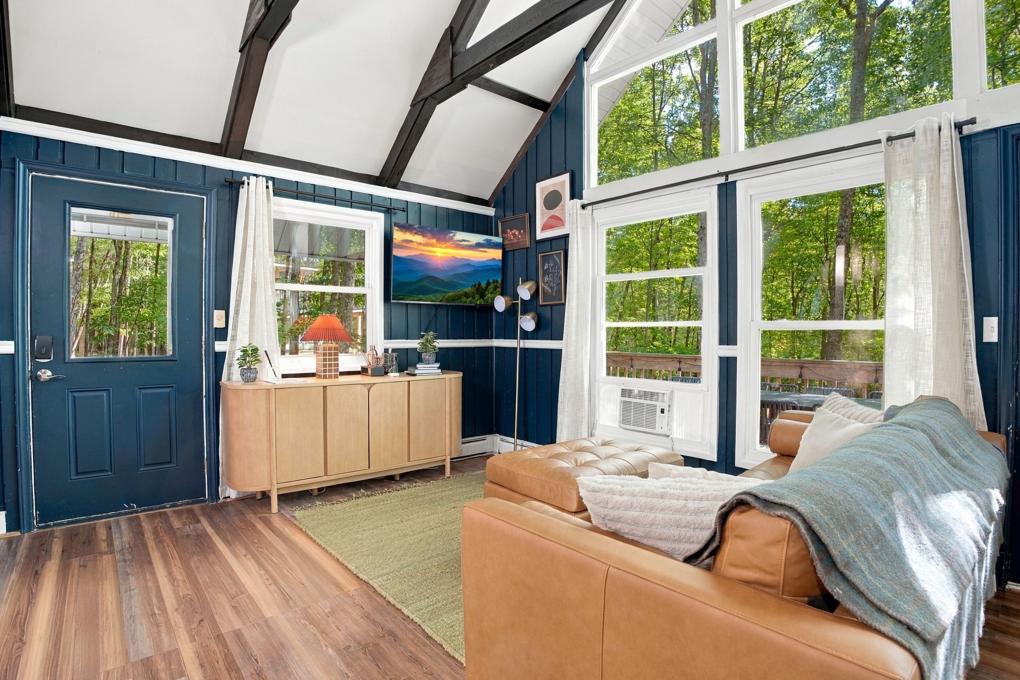 A room with a wooden floor, a leather sofa, a cabinet, and a painting on the wall.