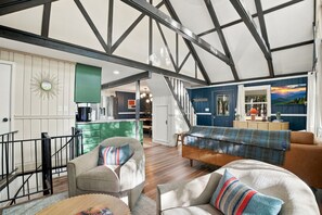 Een ruime woonkamer met een hoge plafond, een trap en een keuken.